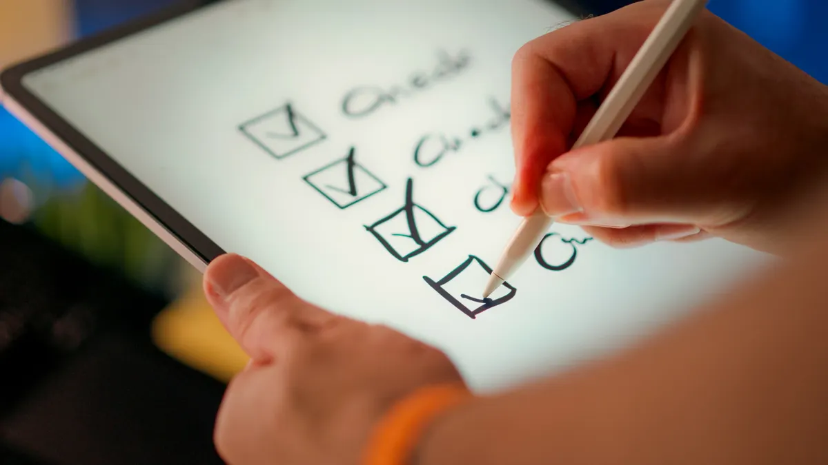 Hand marking a checklist on a tablet